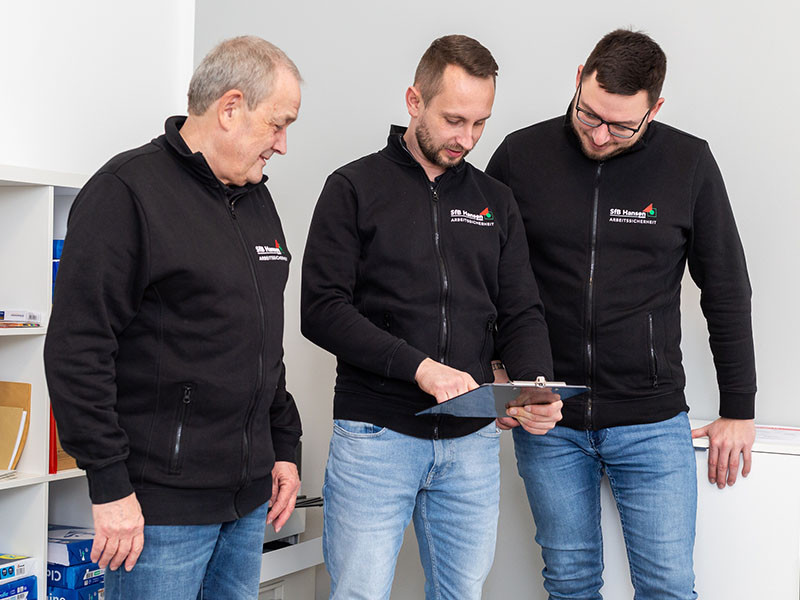 Das Team der SfB Hansen GmbH in Arbeitskleidung bei der Projektbesprechung